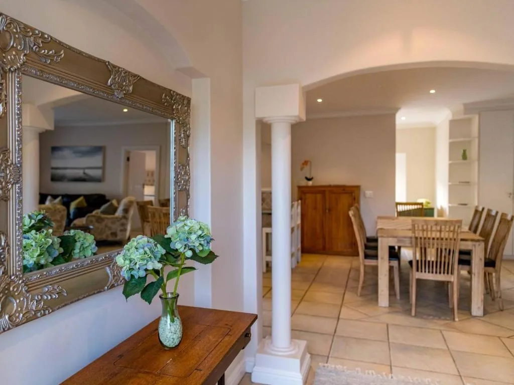 Ornate mirror with blue hydrangeas in vase, open-plan interior visible