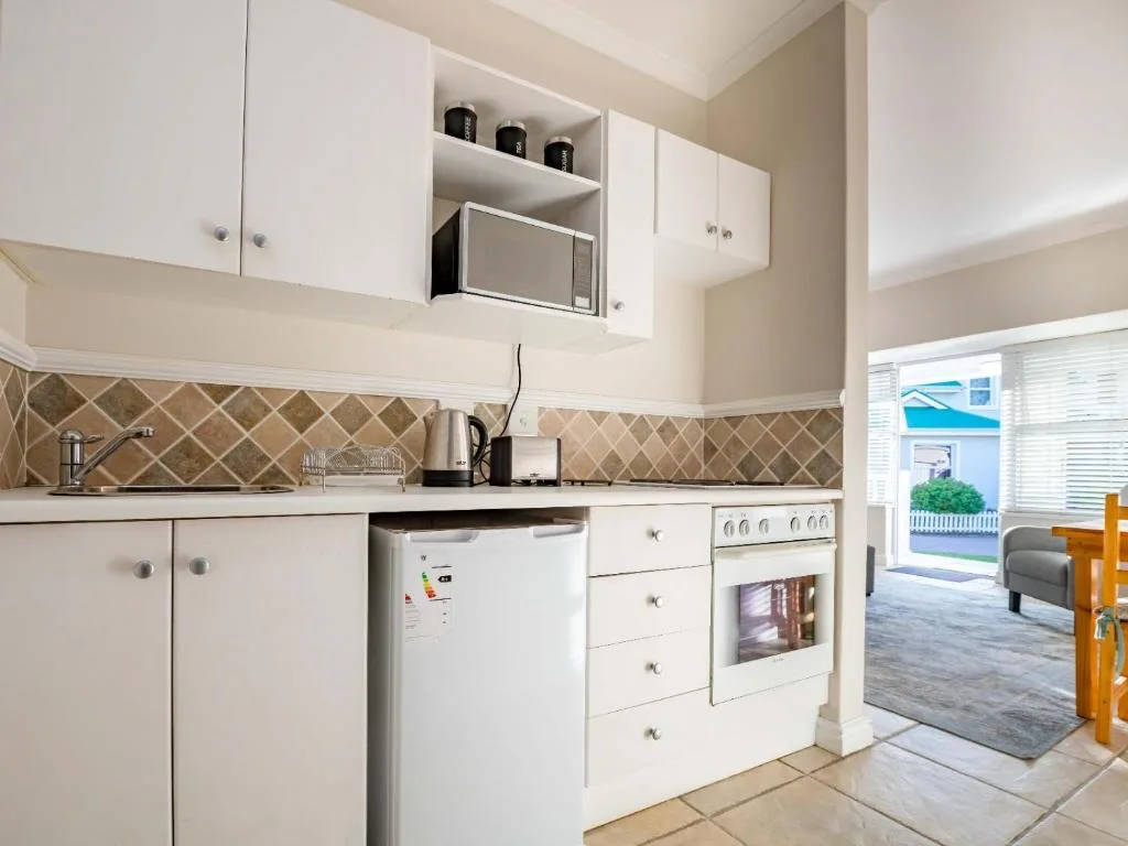 White kitchen with stove, refrigerator, and patterned backsplash tiles