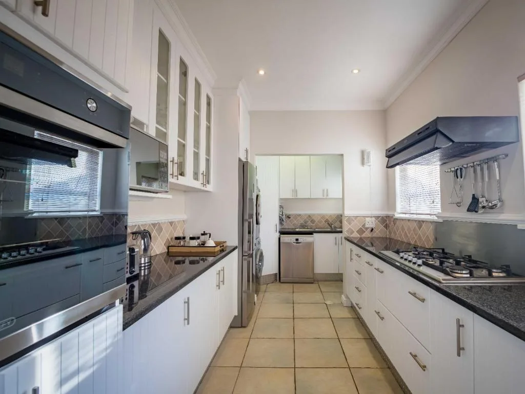 Modern galley kitchen with white cabinetry, black appliances, and patterned backsplash
