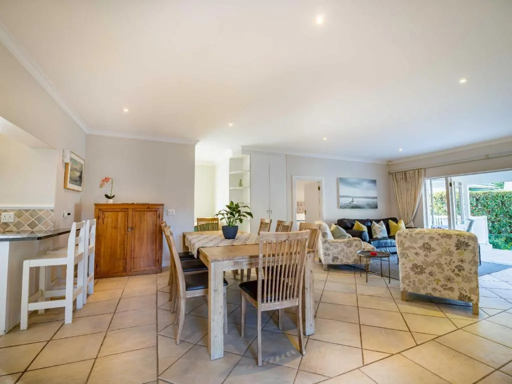 Open-plan living room with dining table, sofa seating, and garden view doors