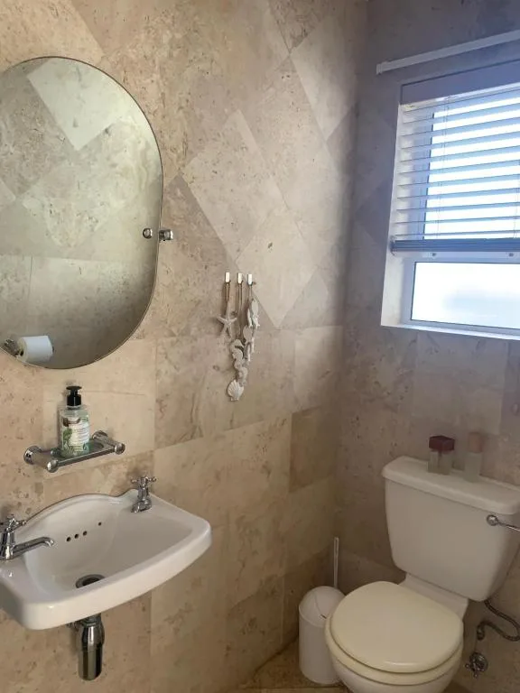Modern bathroom with oval mirror, wall-mounted sink, and toilet fixture