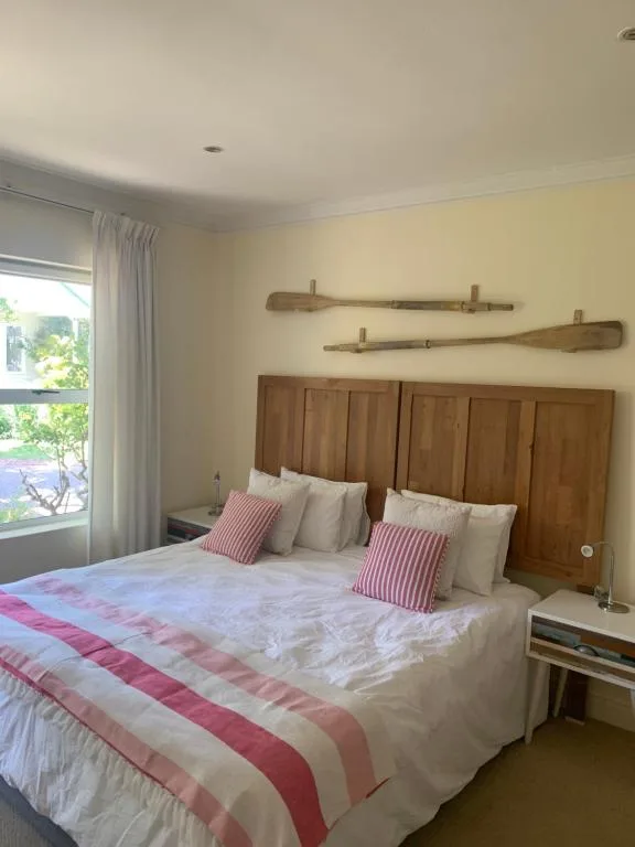 Bright bedroom with wooden headboard, pink striped bedding, and garden views