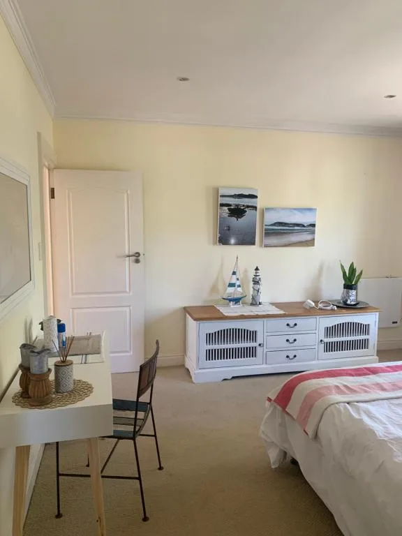 Bright bedroom with double bed, desk, and white coastal-style dresser