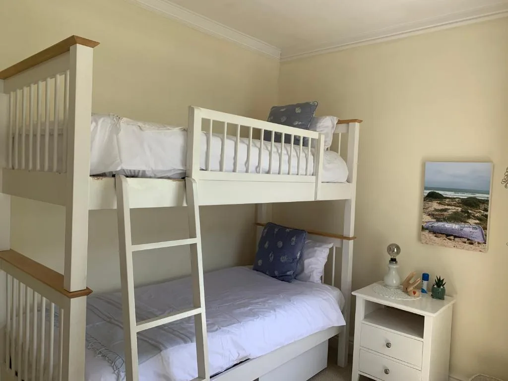 Bright bedroom with white bunk beds and wooden accents throughout