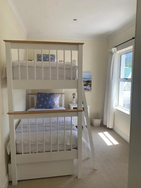 Bright bedroom with white bunk beds and ocean view through glass doors