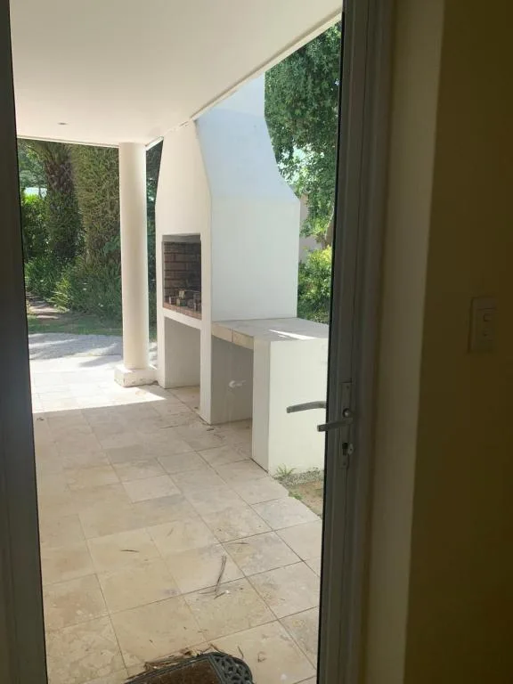 Covered outdoor patio with tile flooring and ivy-covered walls, opening to garden