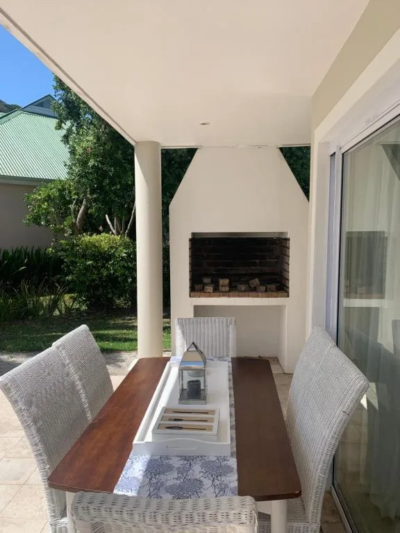 Covered patio with wooden dining table, wicker chairs, and fireplace