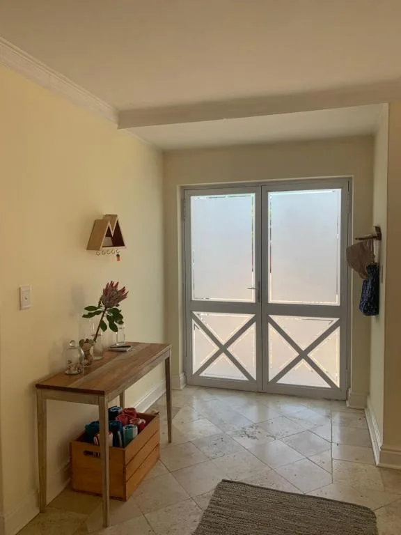 Bright entryway with wooden desk, potted flowers, and glass doors