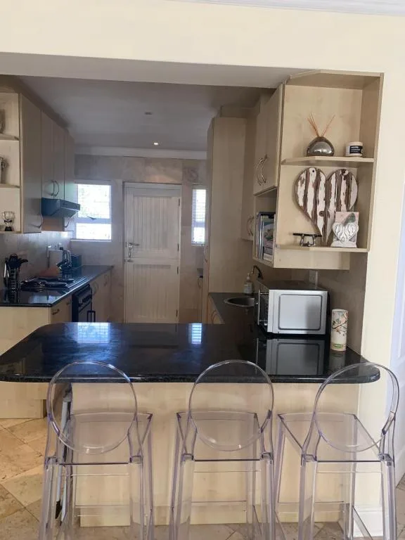 Modern kitchen with black countertop, stove, and transparent bar seating chairs