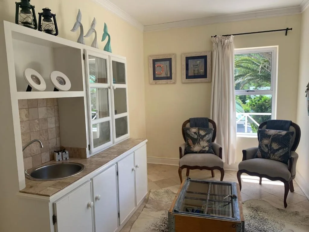 Open-plan lounge with comfortable armchairs, kitchenette, and garden views