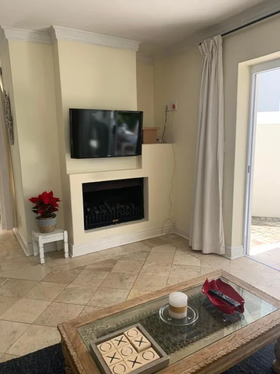 Bright lounge with fireplace, wall-mounted TV, and patio doors