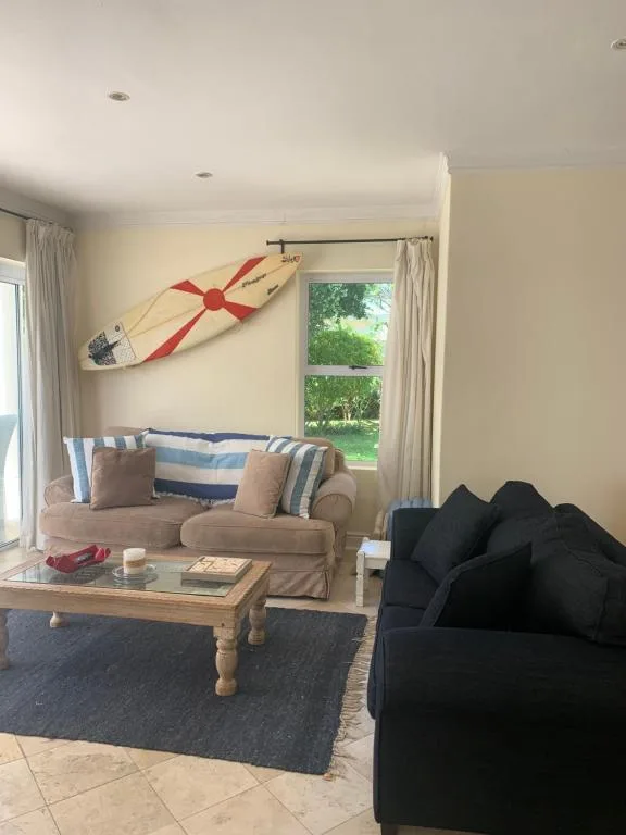 Bright lounge with beige sofa, black armchair, wooden table, and coastal decor