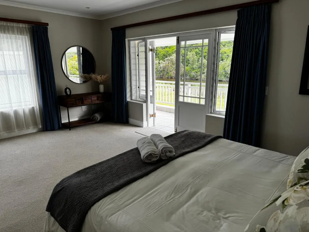 Spacious bedroom with bed, vanity mirror, and garden views through glass doors