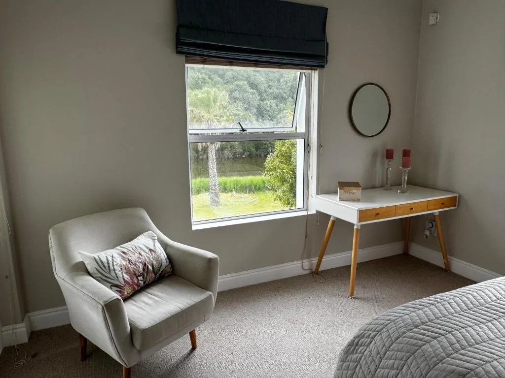 Bright bedroom with armchair, vanity desk, and scenic lagoon view window