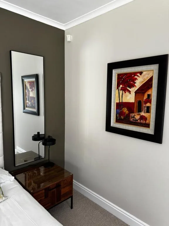 Bedroom corner with wooden furniture, framed artwork, and modern decor