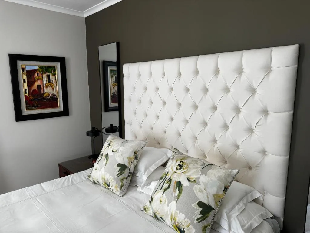 Modern bedroom with white tufted headboard and floral decorative pillows