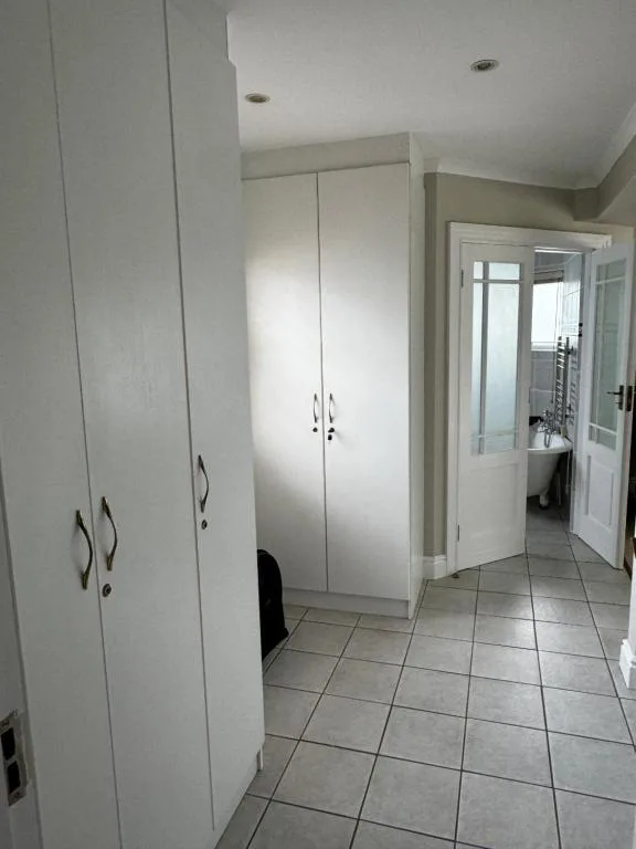 Bedroom with built-in white wardrobes and tile flooring