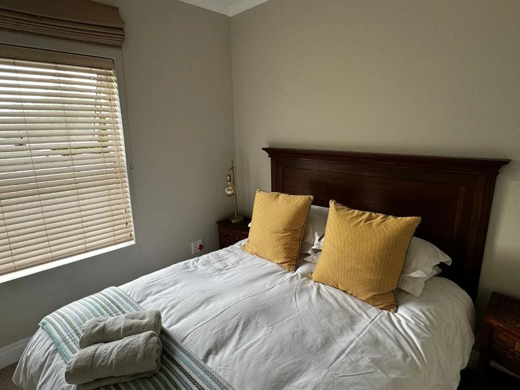 Neat bedroom with dark wooden headboard and yellow accent pillows