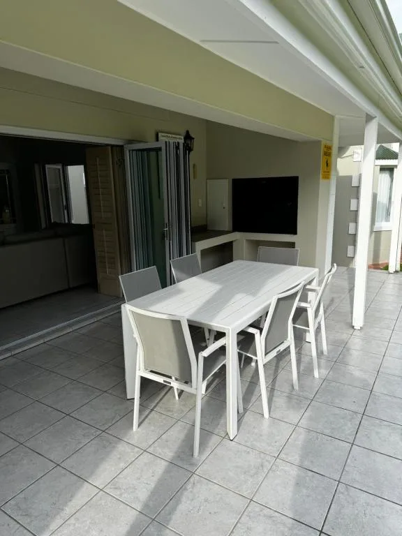 Outdoor patio area with white dining table and chairs under covered roof