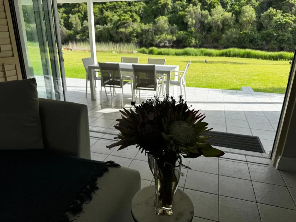 Outdoor patio with dining table and lush green lawn beyond