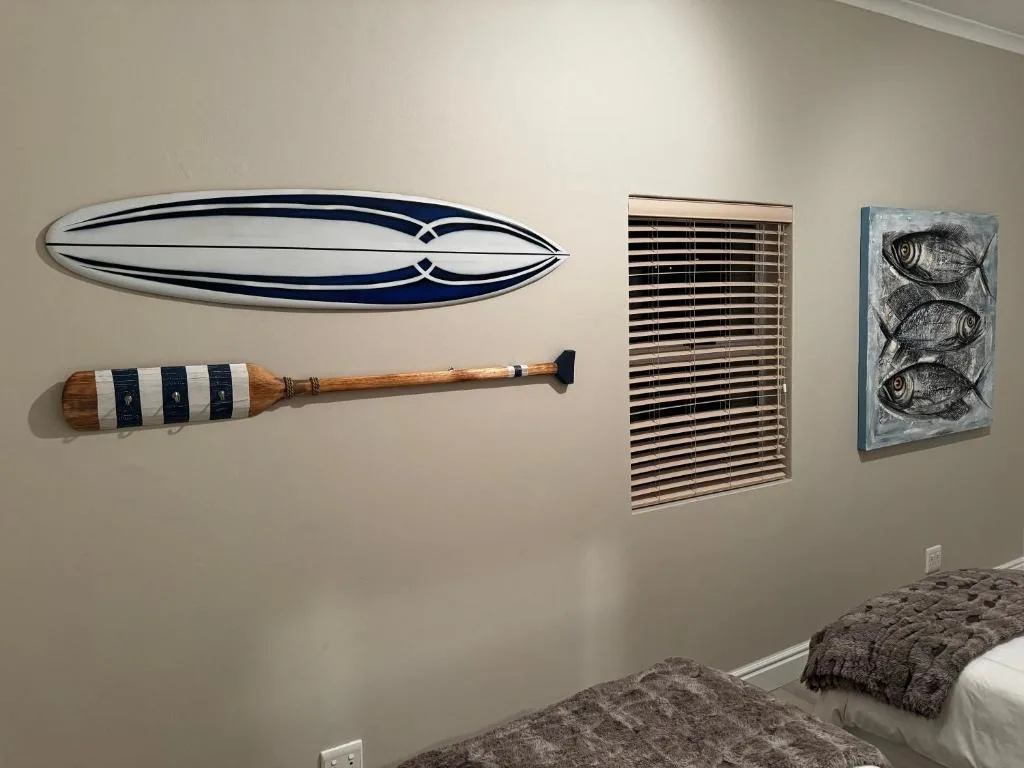 Nautical wall decor featuring surfboard, oar, and fish artwork