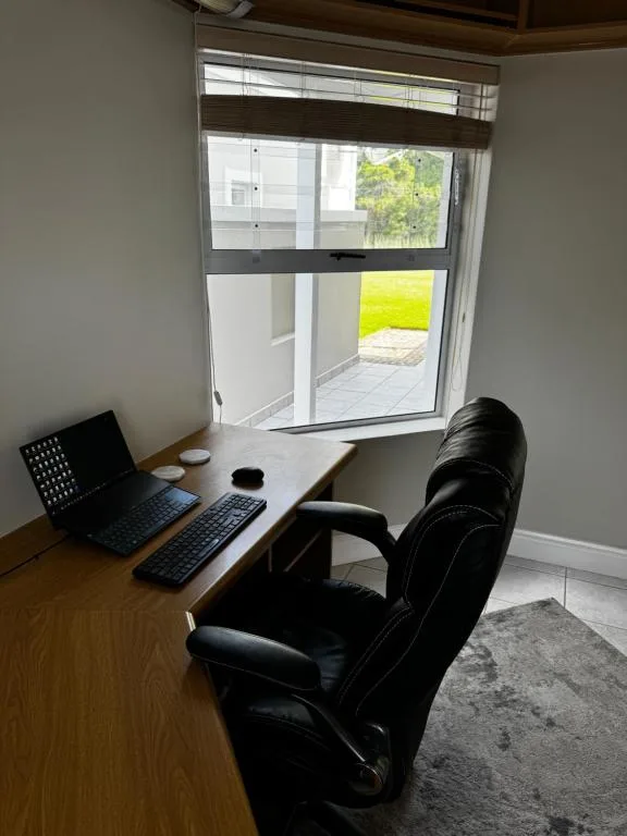 Home office workspace with laptop and chair overlooking garden