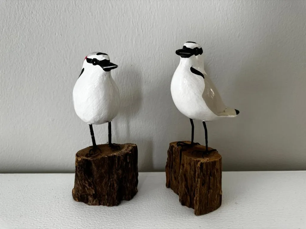 Two decorative white bird figurines on driftwood bases, coastal decor