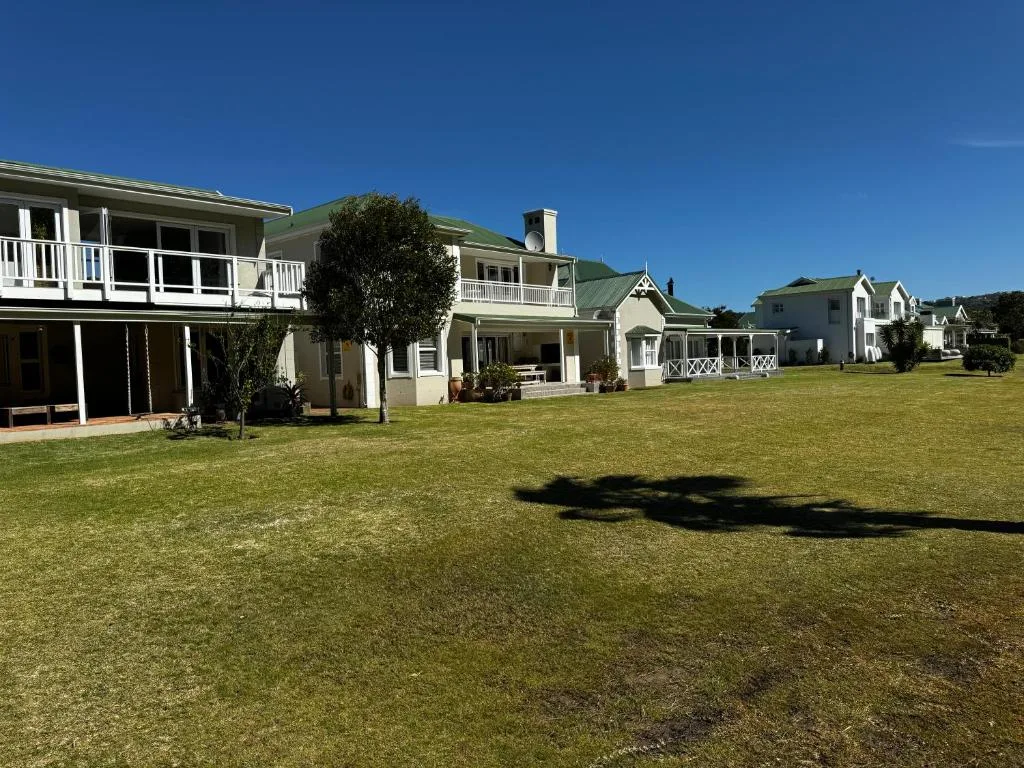 White farmhouse with green roof and wraparound decks overlooking manicured lawn