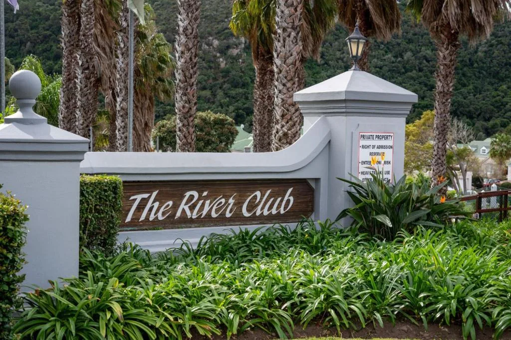 The River Club entrance sign with white pillars and palm trees backdrop