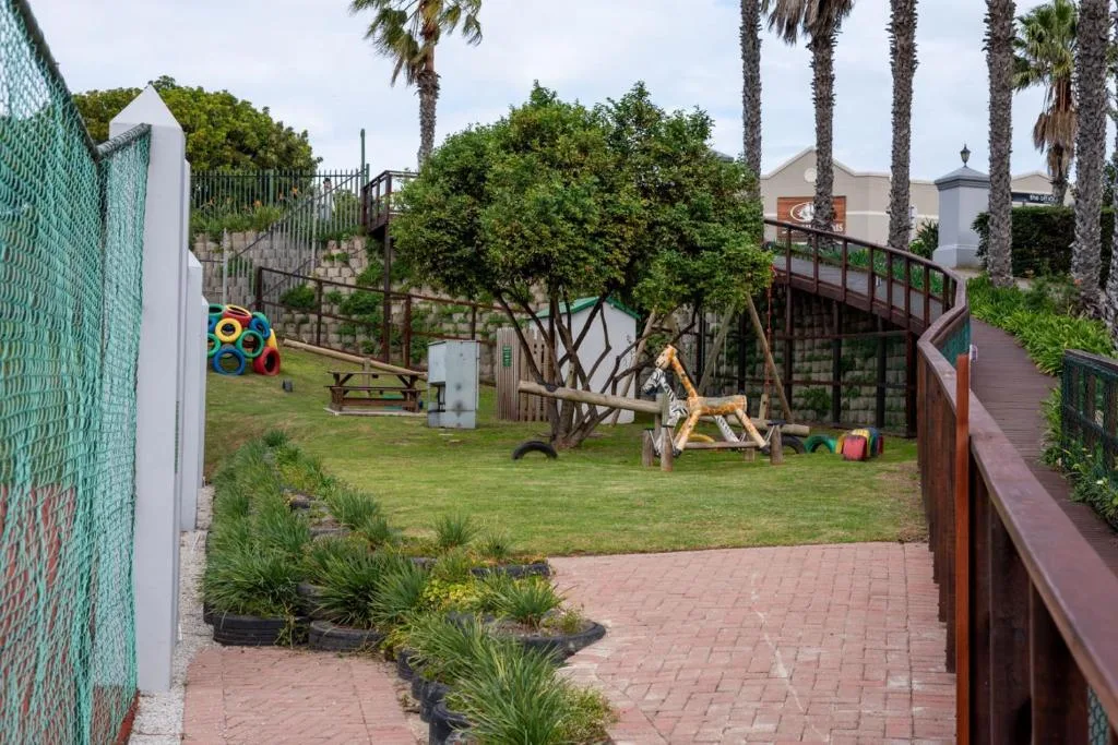 Spacious garden with lawn, palm trees, wooden deck and child's play equipment