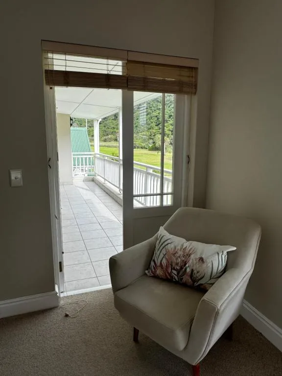 Cream armchair with cushion overlooking garden through glass doors