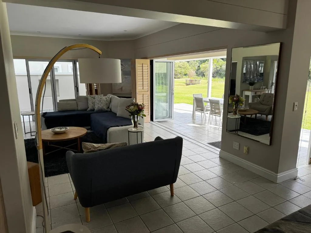 Modern lounge with dark sofas, arc lamp, and garden views through glass doors