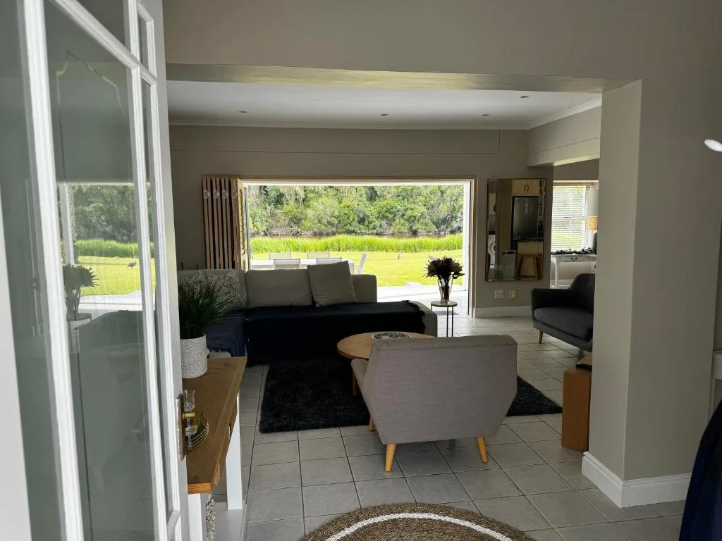 Bright lounge with sofa, armchair, and scenic garden view through large windows