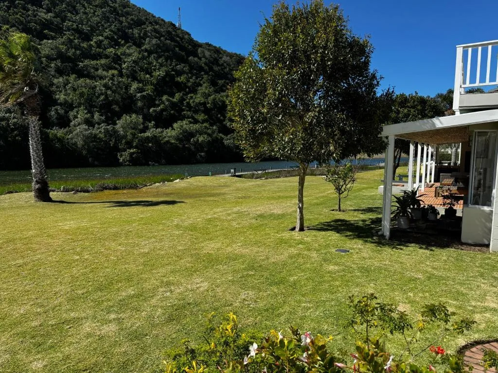 Spacious lawn with lagoon view, forested hills, and modern house structure