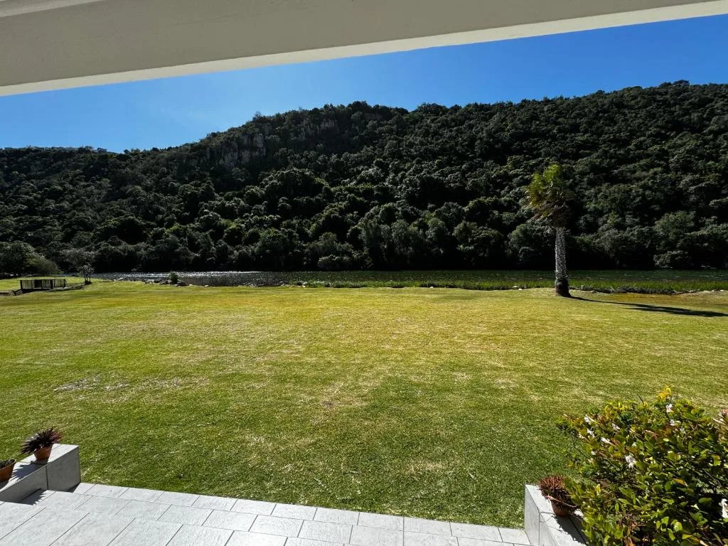 Scenic river valley with lush forested mountains and manicured lawn