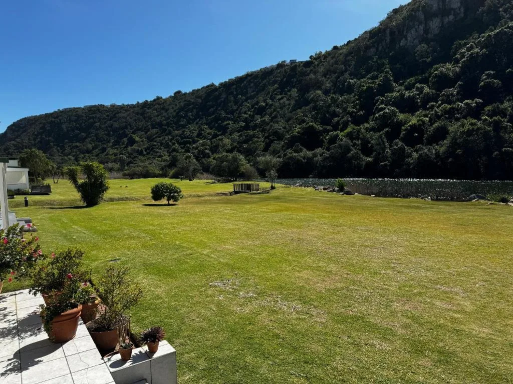 Expansive green lawn with river and forested mountain landscape backdrop