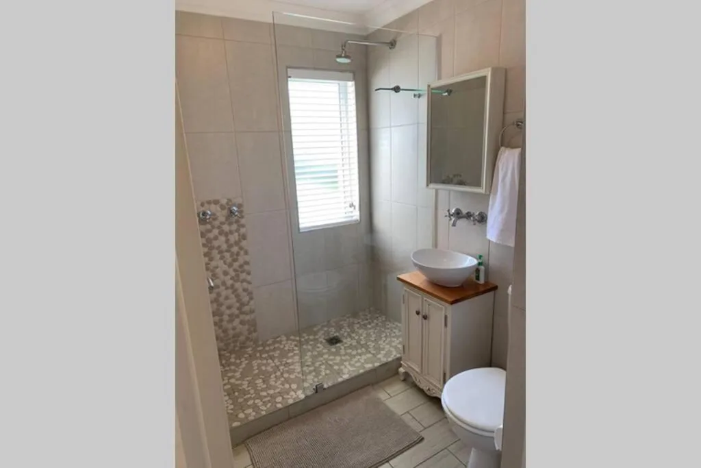 Modern bathroom with glass shower enclosure, round basin sink, and toilet