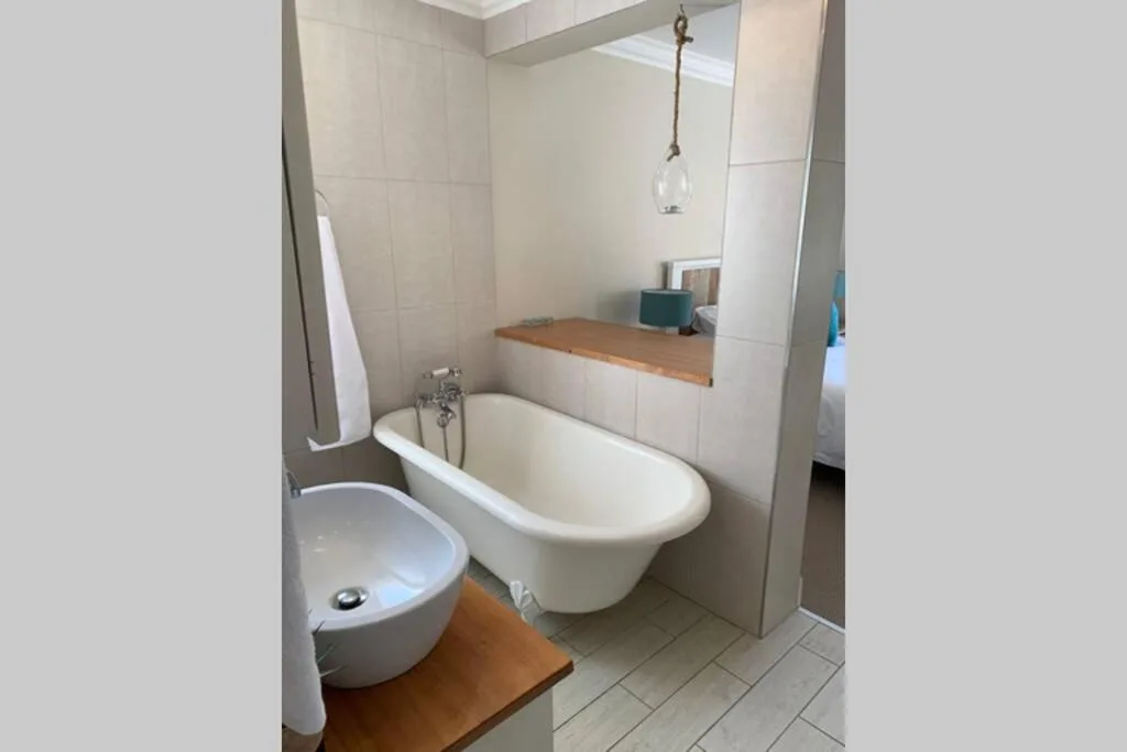 Modern bathroom with freestanding bathtub, round sink, and wooden vanity