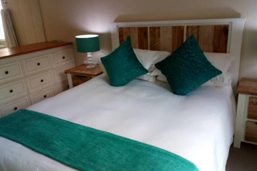 Spacious bedroom with queen bed, teal cushions, and white cabinetry storage