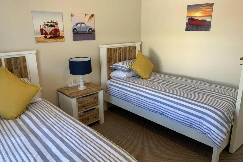 Twin bedroom with striped bedding, yellow cushions, wooden headboards