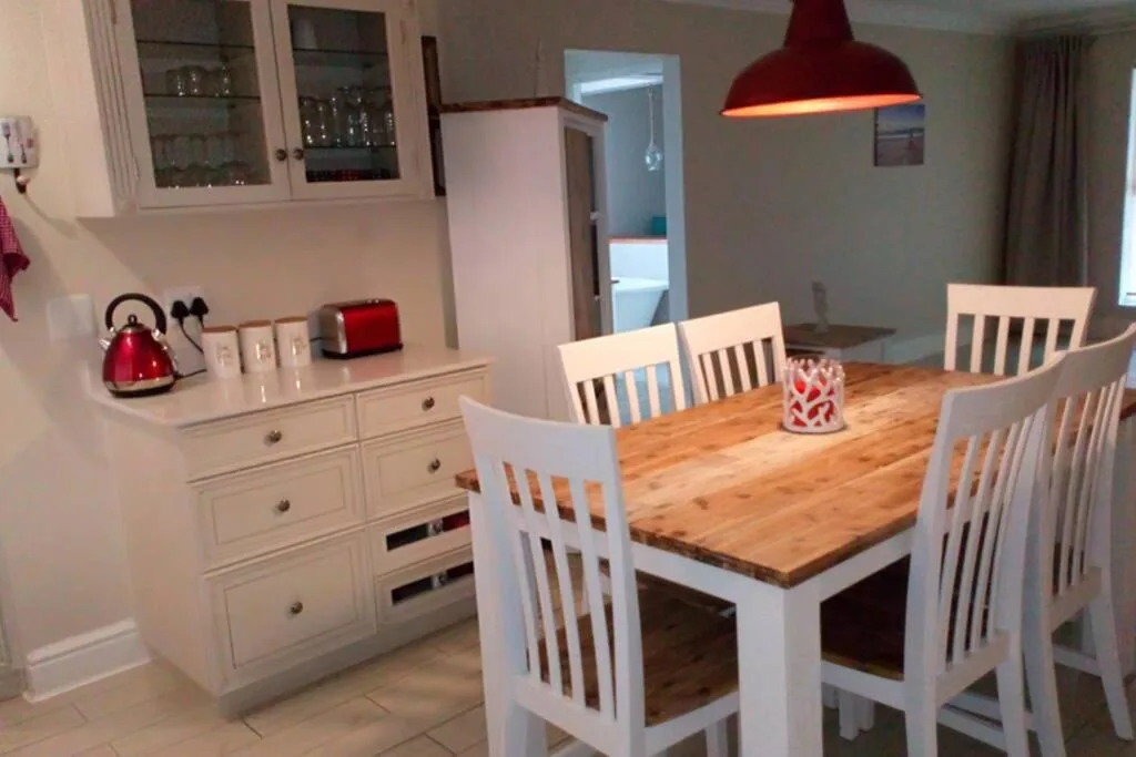 Wooden dining table with white chairs under red pendant lamp