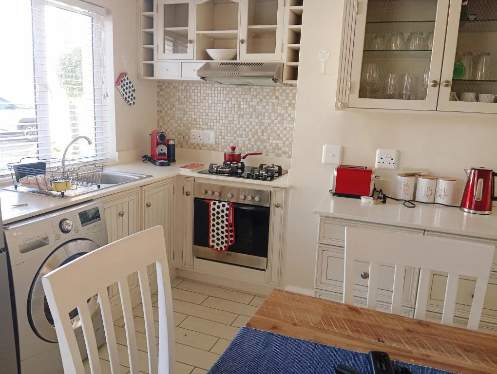 Cream kitchen with gas stove, white cabinetry, and tiled backsplash
