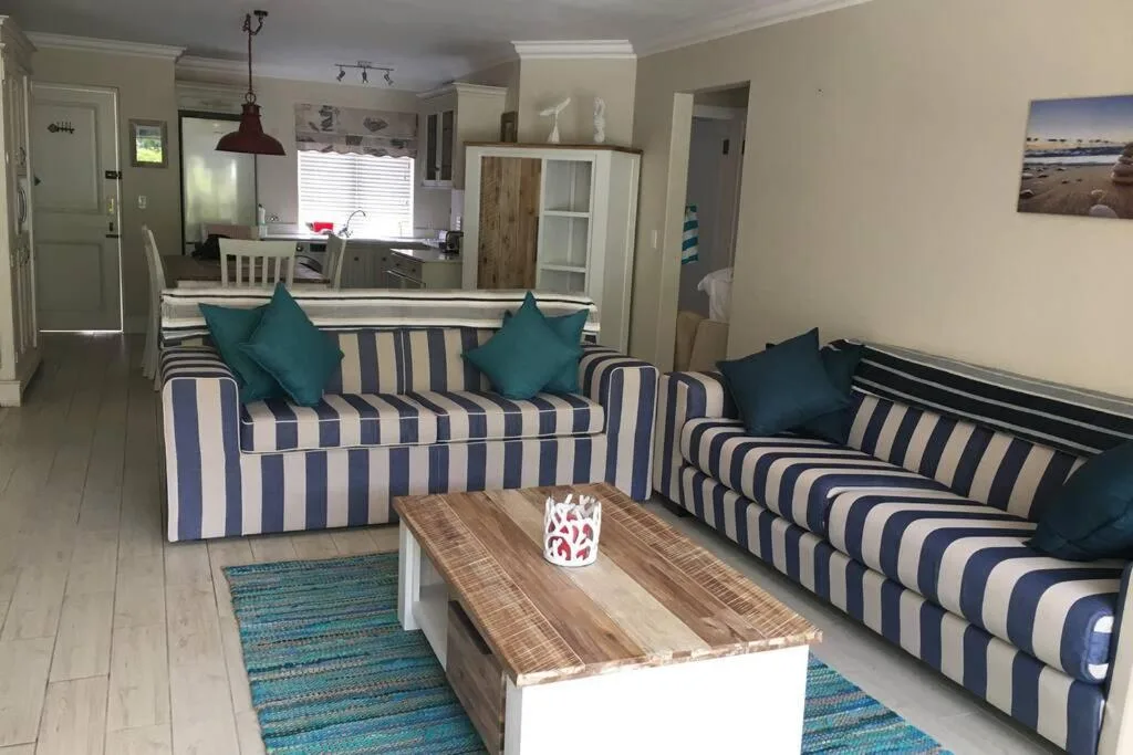 Spacious lounge with striped sofas, teal cushions, and wooden coffee table