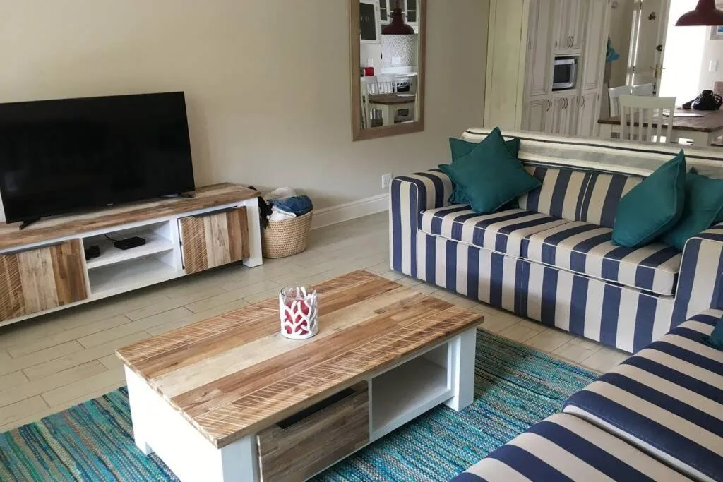 Spacious lounge with striped sofa, wooden coffee table, and flat-screen TV