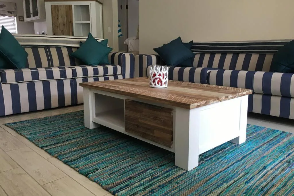 Striped sofas with teal cushions and wooden coffee table in lounge area