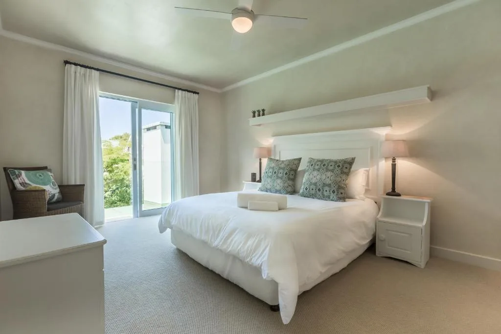 Bright modern bedroom with queen bed, bedside tables, and garden view doors