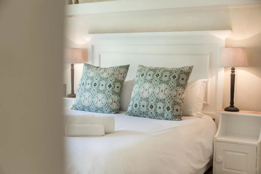Bright bedroom with white headboard, patterned cushions, and bedside lamps