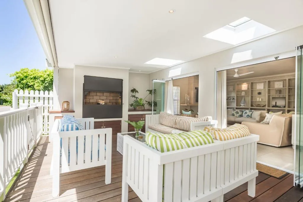 Covered deck with loungers, fireplace, and views to garden