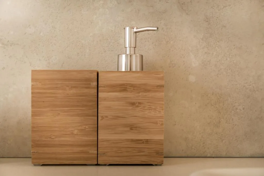 Wooden soap dispenser with stainless steel pump on neutral background