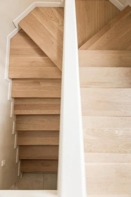 Wooden staircase with white handrail leading downstairs